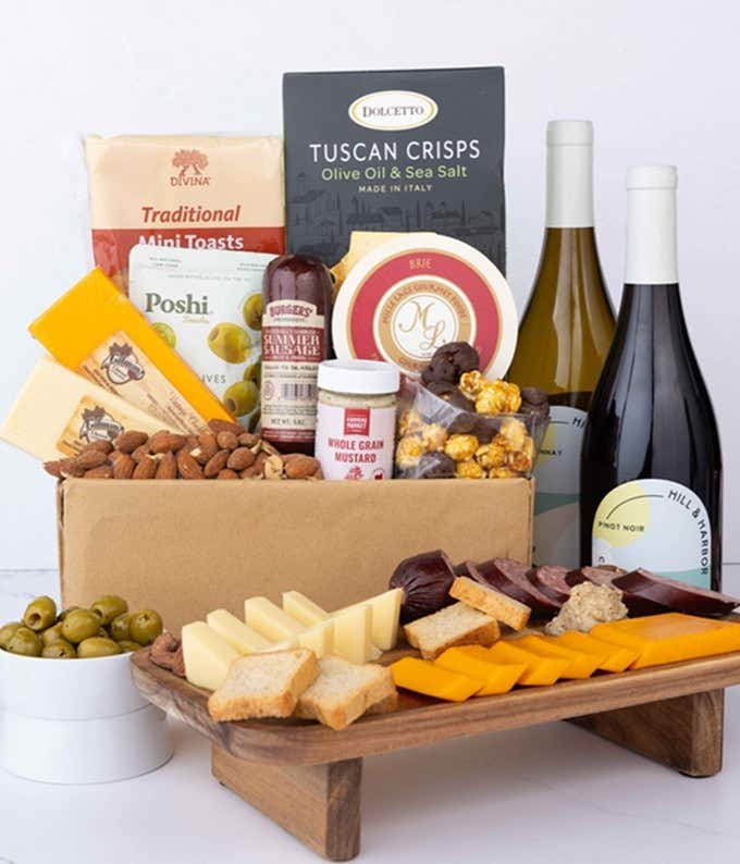 An abundant gift box filled with two bottles of California wine - red & white, assorted crackers, three cheeses, summer sausage, and snacks to make an amazing charcuterie spread. 