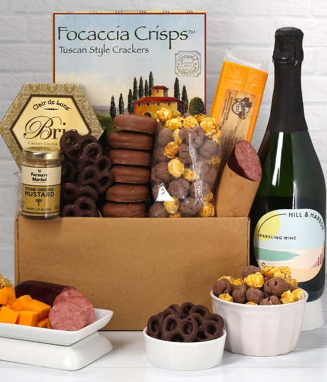 A gift set featuring a bottle of Hill &amp; Harbor Sparkling Wine, focaccia crisps, 2 cheeses, mustard, summer sausage, caramel popcorn, chocolate pretzels, and 6 chocolate-covered Oreos for a sweet and savory gourmet experience.