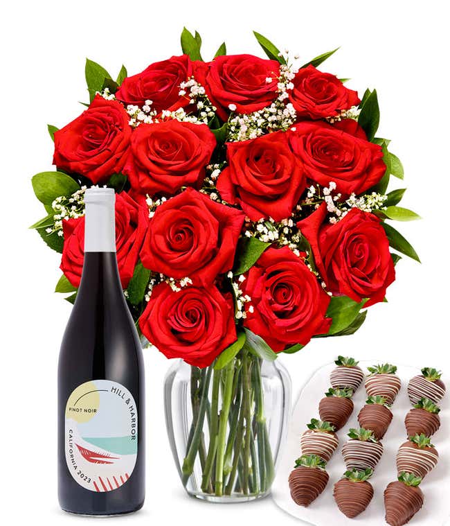 A bouquet of 1 dozen red roses in a clear glass vase is displayed beside a bottle of Hill &amp; Harbor Pinot Noir and an arrangement of 12 chocolate-covered strawberries.