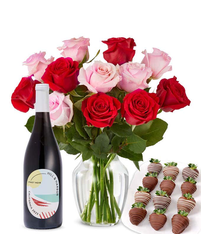 A mixed bouquet of 1 dozen red and blush roses in a clear vase is paired with a bottle of Hill & Harbor Pinot Noir and 12 chocolate-covered strawberries.