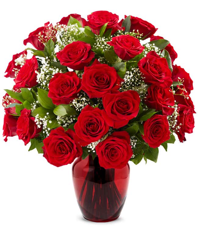 A classic arrangement of one dozen red roses, accented with baby's breath, elegantly presented in a red glass vase. This timeless display offers a romantic and sophisticated touch.