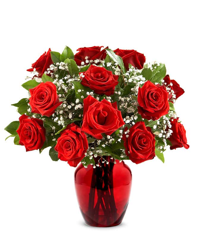 A classic arrangement of one dozen red roses, accented with baby's breath, elegantly presented in a red glass vase. This timeless display offers a romantic and sophisticated touch.