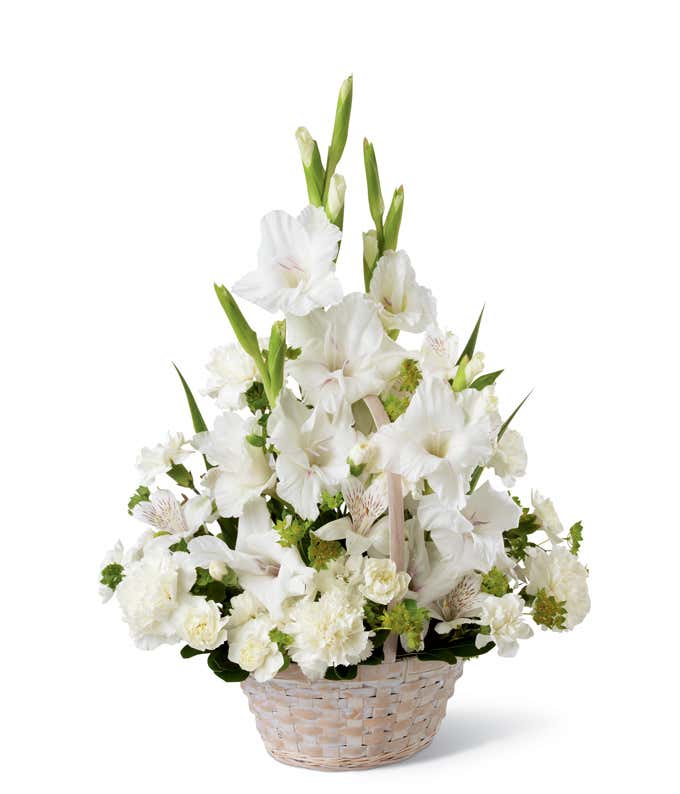 White basket arrangement with white gladiolus, white carnations, white alstroemeria, and greenery, styled in a fan shape with tall blooms rising in the center.