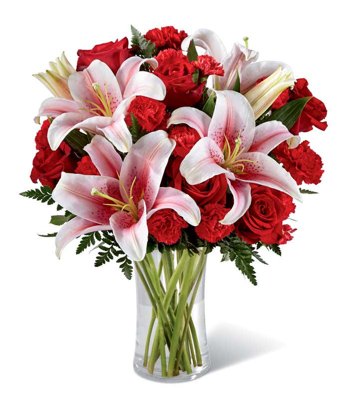 Elegant bouquet featuring red roses, red spray roses, and stargazer lilies in a clear glass vase. A romantic floral arrangement perfect for Valentine’s Day, anniversaries, or expressing heartfelt affection.