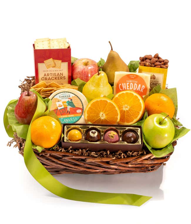 A basket filled with fresh fruits, crackers, cheese crisps, almonds, honey mustard, and assorted caramels, adorned with a green ribbon. 