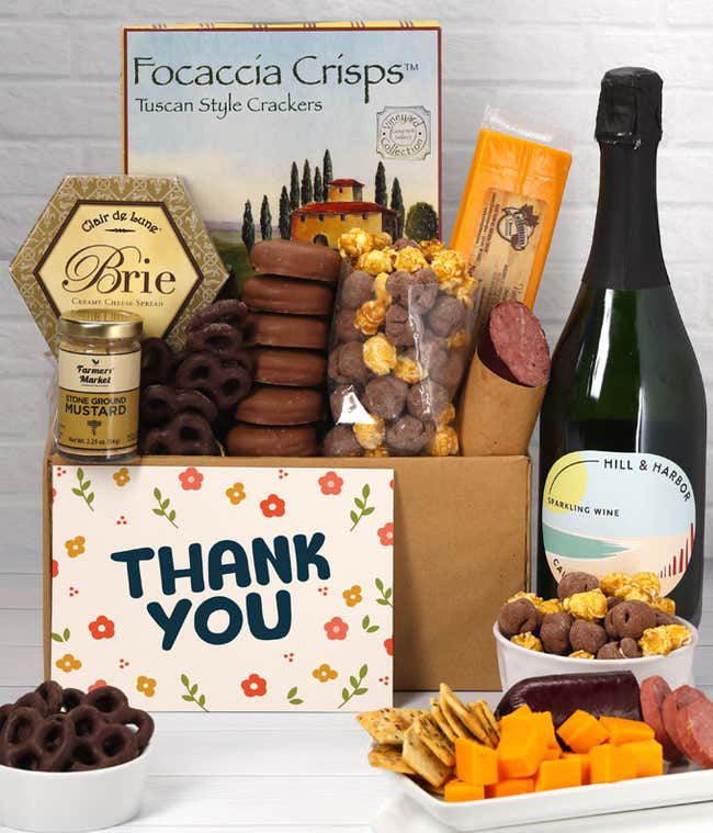 A gift set featuring a bottle of California Sparkling Wine, focaccia crisps, two cheeses, mustard, summer sausage, caramel popcorn, chocolate pretzels, six chocolate-covered Oreos and a Thank You card to complete the gourmet experience.