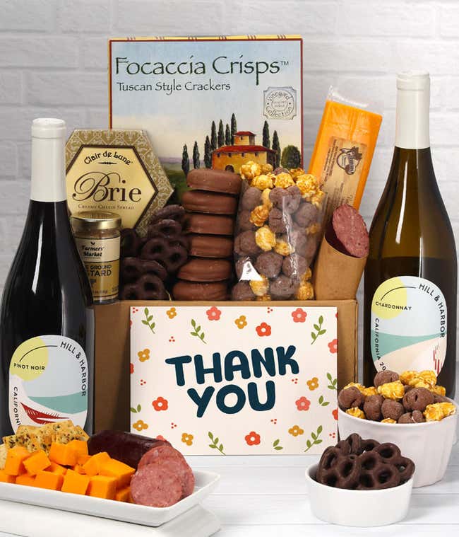 A gift set featuring two bottles of Hill &amp; Harbor wine - white and red, focaccia crisps, two cheeses, mustard, summer sausage, caramel popcorn, chocolate pretzels, six chocolate-covered Oreos and a Thank You card to complete the gourmet experience.