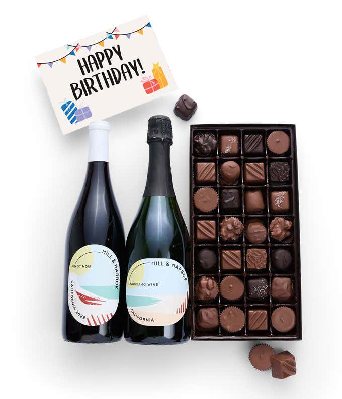 A gift box containing two bottles of California Wine - Pinot Noir & Sparkling Wine, a 1 lb box of 28 assorted gourmet chocolates in a grid, and a birthday message card.   A refined combination perfect for birthday celebrations.