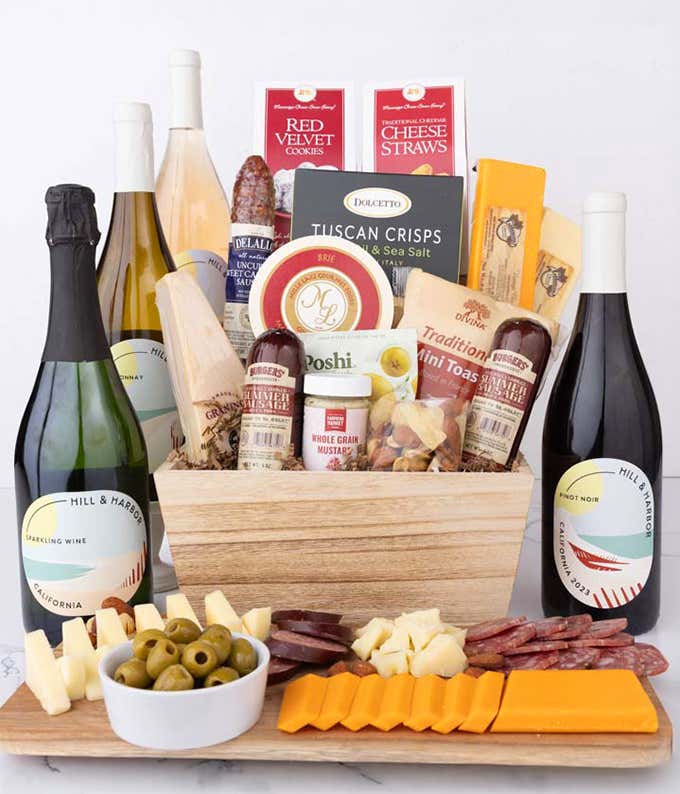 Wooden basket filled with 4 cheeses, 3 sausages, crackers, cookies, nuts, mustard, olives and crisps alongside 4 bottles of wine - Pinot Noir, Chardonnay, Rosé & Sparkling Wine.